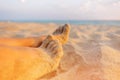 Close-up view of female barefoot legs on sand.