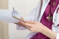 Close up view of female doctor hands filling patient history