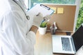 Close-up view of female doctor hands filling patient registration form.