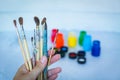 Close up view of female hand with set of paint brushes on blue b Royalty Free Stock Photo