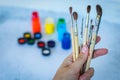 Close up view of female hand with set of paint brushes on blue blurred background with paints cans Royalty Free Stock Photo