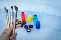 Close up view of female hand with set of paint brushes on blue blurred background with paints cans Royalty Free Stock Photo