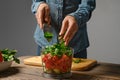 Close up view of female hands dropping chopped cilantro into blender