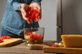 Close up view of female hands dropping chopped red bell pepper into blender