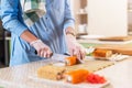 Close-up view of female hands in gloves cooking traditional Japanese sushi rolls cutting with knife in kitchen