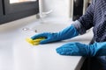 Female hands in rubber gloves cleaning kitchen counter with rag