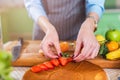 Close-up view of female hands putting sliced strawberry on a cake layer. Woman making berry pie in the kitchen