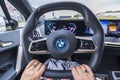 Close up view of female hands on steering wheel of electric car BMW IX40 while driving.