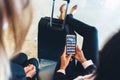 Close-up view of female holding smartphone with different applications on screen sitting with her legs resting on her