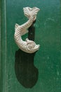 Close-up view of the fish shaped knocker on a green wooden door Royalty Free Stock Photo