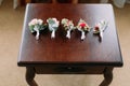 Close-up view of the five boutonnieres of coloutful roses on the table.