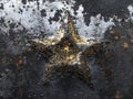 A gilded star, textured and worn, rests on a dark, metallic background splattered with silver and Royalty Free Stock Photo