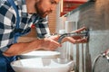 Close up view. Fixing water tap. Plumber in blue uniform is at work in the bathroom