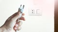 A hand picks up three pin electrical plug. Royalty Free Stock Photo