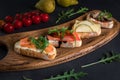 Close-up view on Four bruschettas lay on wooden board. Appetizers with tomato, mozzarella, pesto, salmon and roast beef Royalty Free Stock Photo