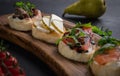 Close-up view on Four bruschettas lay on wooden board. Appetizers with tomato, mozzarella, pesto, salmon and roast beef Royalty Free Stock Photo