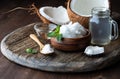 Close up view of coconut oil, MTC medium chain triglycerides and coconut water with a coconut cracked in half in behind.