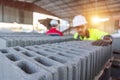 A close-up view of fresh concrete cinder blocks with two construction managers inspecting product quality in the blurred Royalty Free Stock Photo