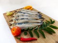 Close up view of Fresh Indian oil sardine on a wooden pad,Decorated with herbs and Vegetables. Royalty Free Stock Photo