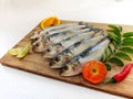 Fresh Indian oil sardine on a wooden pad,Decorated with herbs and Vegetables.White Background Royalty Free Stock Photo