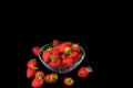 Close up view of fresh red strawberry in glass bowl on blackbackground.