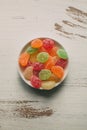 Close up view of fruity jelly candies on a bowl. Colorful sugary candies on white wooden background. Royalty Free Stock Photo