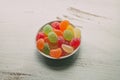 Close up view of fruity jelly candies on a bowl. Colorful sugary candies on white wooden background. Royalty Free Stock Photo