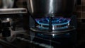 Gas stove cooking food in the metal pot at the kitchen with blue fire flame Royalty Free Stock Photo