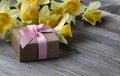 Close up view of a gift box with yellow daffodil on weathered wooden planks for Mothers day love holiday Royalty Free Stock Photo