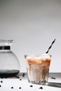close up view of glass of cold brewed coffee with straw, coffee maker and roasted coffee beans