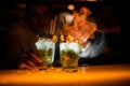 close-up view on glasses with iced mojito cocktail on which hand of bartender splashes and sets fire