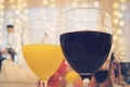 Close-up view of glasses with red wine and orange juice on a table in restaurant at the garlands curtain background. Filled glasse Royalty Free Stock Photo