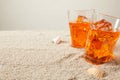 close up view of glasses of refreshing cocktails on sand with seashells on grey bakgorund