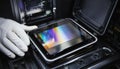 Close up view of gloved hand placing iridescent microchip into precision testing machine within dark industrial Royalty Free Stock Photo