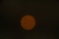 Close-up view of a glowing orange circle seen through a hexagonal mesh, likely portraying a light source or fire. Unique Royalty Free Stock Photo