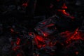 Glowing red embers and burning coals in dark fire pit Royalty Free Stock Photo