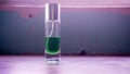 The close up view of the green perfume liquid in a glass bottle with light flare on the background