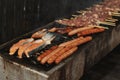 Close-up view of Grilling Chicken Meat, fish salmon steak and Sausages on long rectangular barbecue with smoke on the street outdo Royalty Free Stock Photo