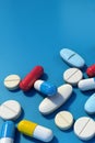 Pile of various medicine pills scattered on blue background