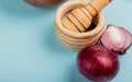 close-up view of half cut and whole red onions and black pepper seeds in garlic crusher on blue background Royalty Free Stock Photo