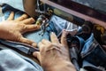 A close up hand is repairing the jeans with an old sewing machine Royalty Free Stock Photo