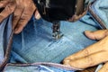 A close up hand is repairing the jeans with an old sewing machine Royalty Free Stock Photo