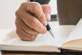 Close up view of hand holding a pen and writing on notebook diary Royalty Free Stock Photo