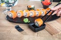 Close up view on hand holding chopsticks and dunk sushi in soy sauce. California roll with salmon. Japanese cuisine. Copy space. Royalty Free Stock Photo