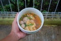 Hand holding a delicious Cuanki on a white bowl. Cuanki is Indonesian street food from Bandung, West Java, Indonesia