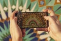 close up view of a hand holding a phone and taking a photo of a moroccan mosaic pattern at Hassan II mosque exterior - Casablanca Royalty Free Stock Photo