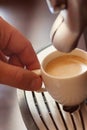 Close up view of the hand of a man working in a coffee house preparing espresso coffee waiting for the coffee machine to finish p