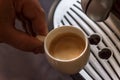 Close up view of the hand of a man working in a coffee house preparing espresso coffee waiting for the coffee machine to finish p