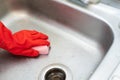 Close up view hand in red cleaning glove using sponge clean the sink in kitchen Royalty Free Stock Photo