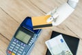 close-up view of hand of robot holding credit card above money and payment terminal Royalty Free Stock Photo